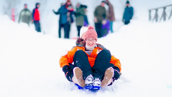 Girls sliding down a hill with a sledge