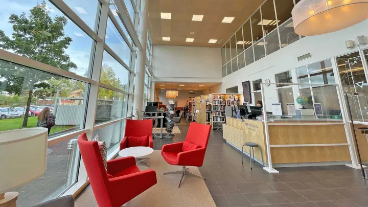 A picture from Lutakko library premises: armchairs in the foreground and customer service desk in the background