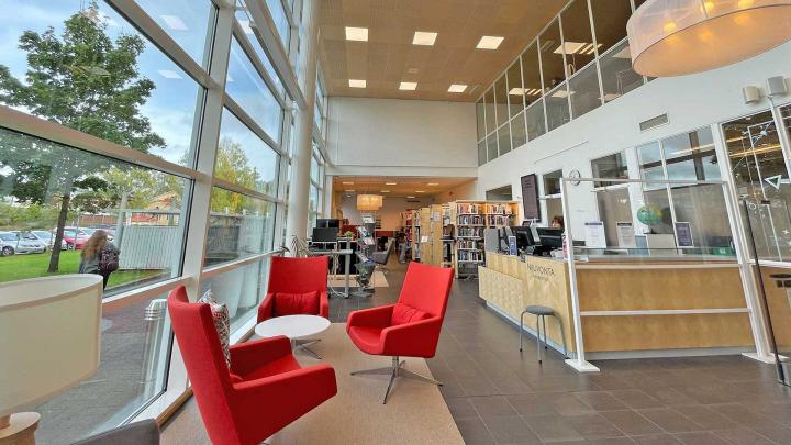 A picture from Lutakko library premises: armchairs in the foreground and customer service desk in the background